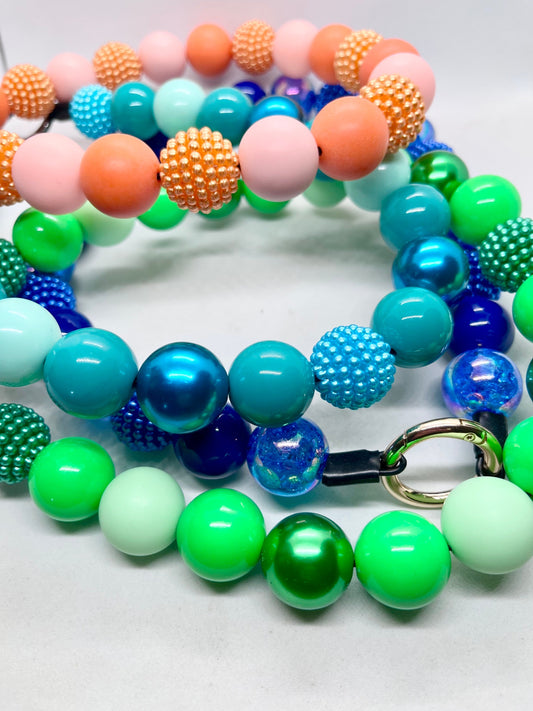 JOOLS LONDON Summer Colour Edit — four beaded dog collars coiled together showing Peachy Keen, Pool Party, Go Green and Teal Me