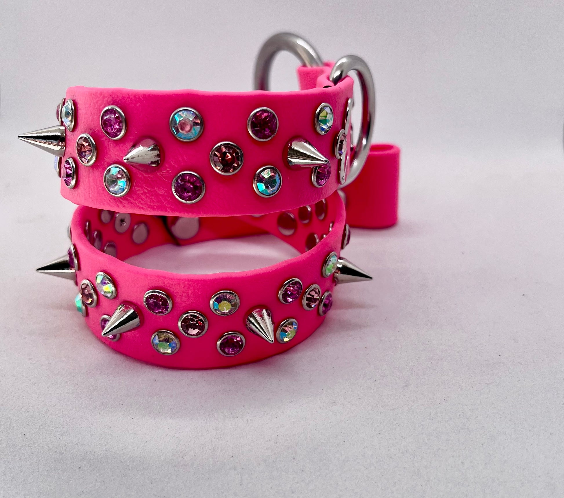 Overhead view of neon pink rhinestone spiked BioThane dog collar showing full stud detail