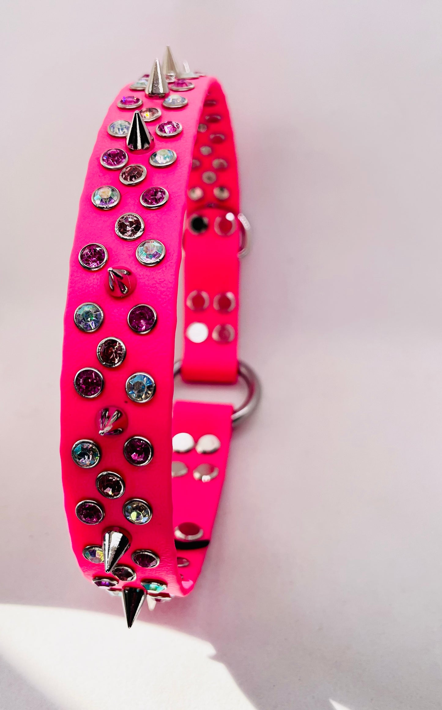 Neon pink BioThane dog collar standing upright showing bold spike studs, mixed crystals and stainless steel O ring | JOOLS LONDON