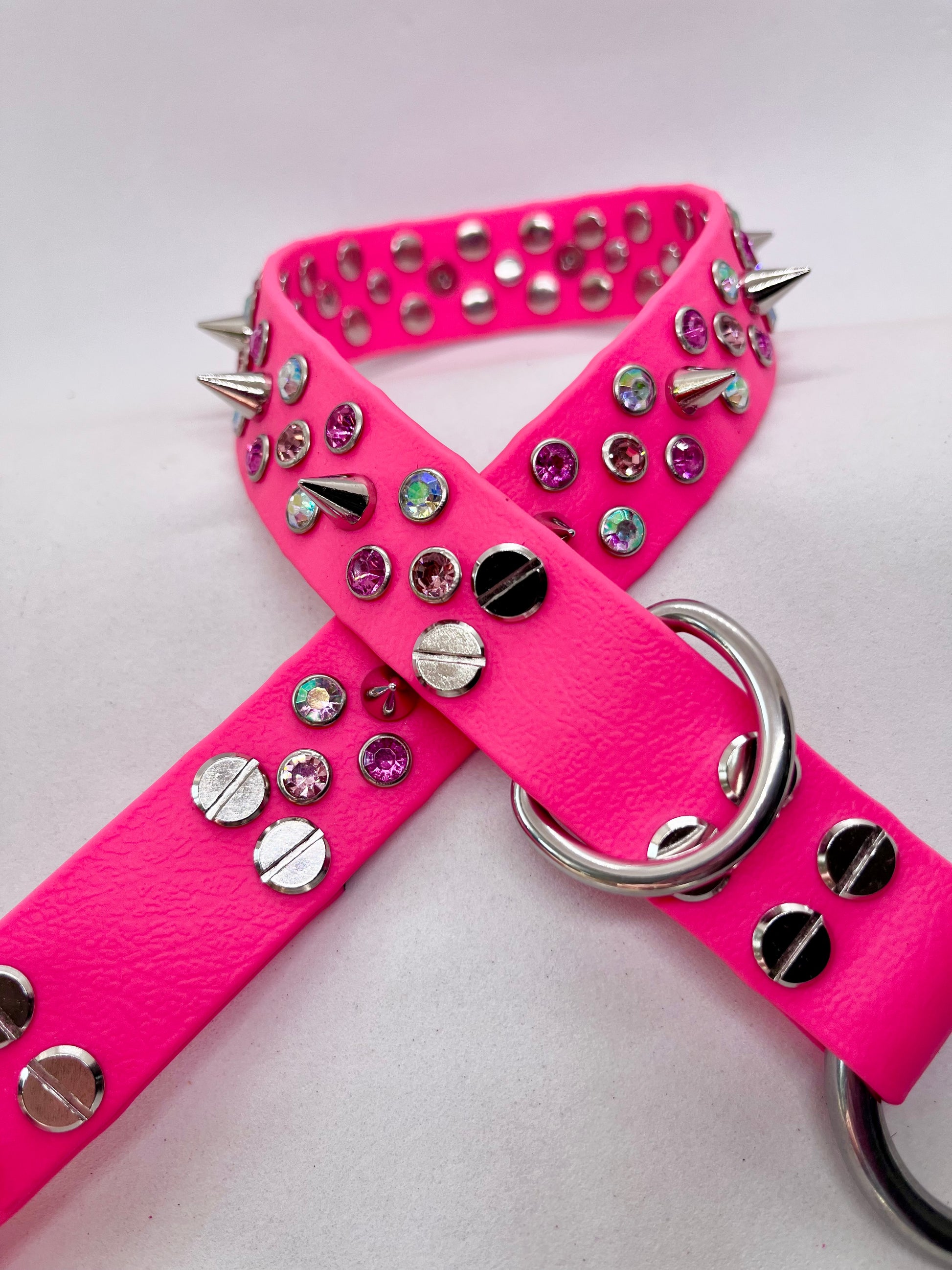 Angled view of neon pink BioThane dog collar showing rhinestone crystals, spikes and stainless steel O ring