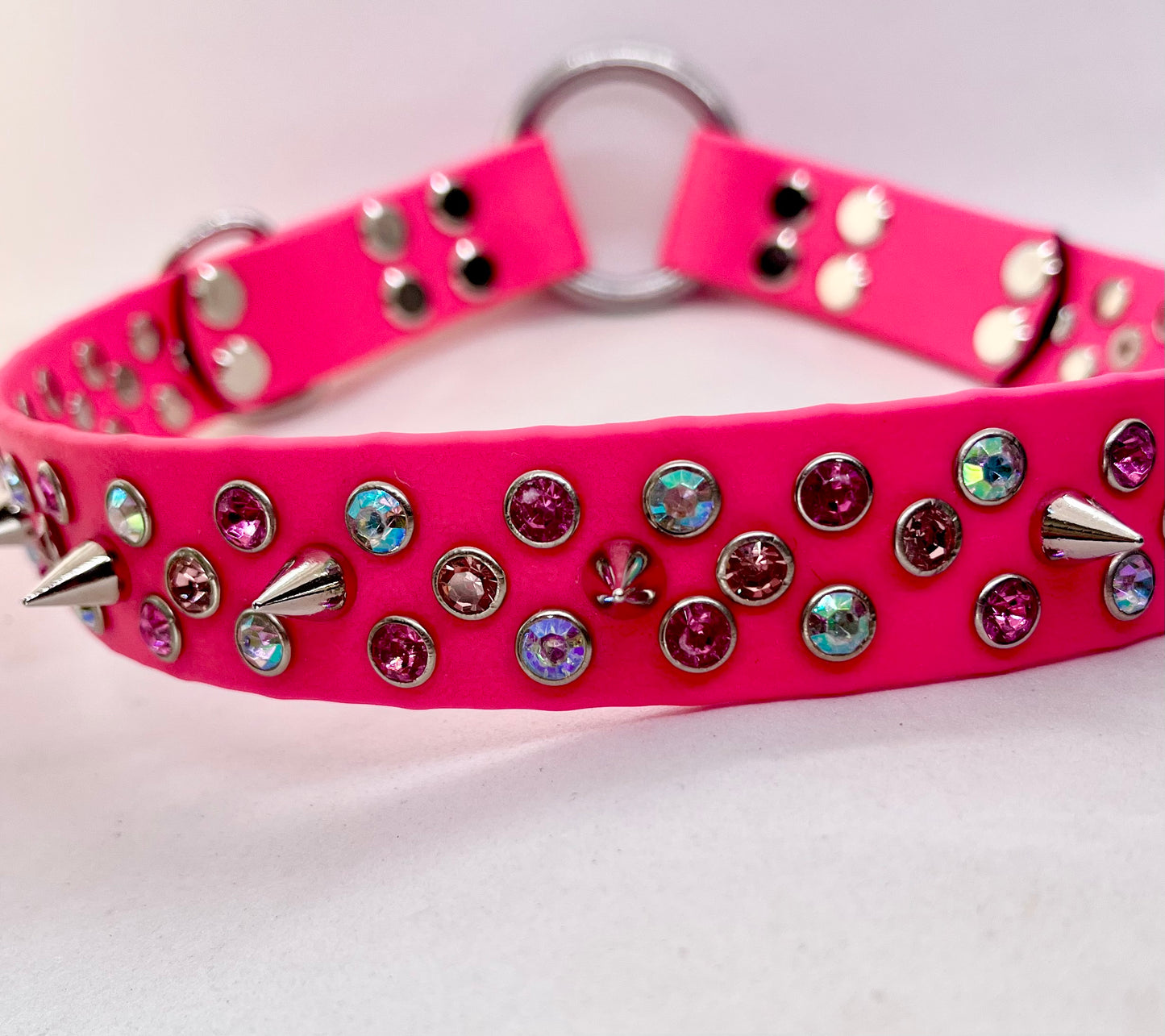 Neon pink BioThane dog collar crossed flat lay showing rhinestone crystals, spikes and stainless steel O ring