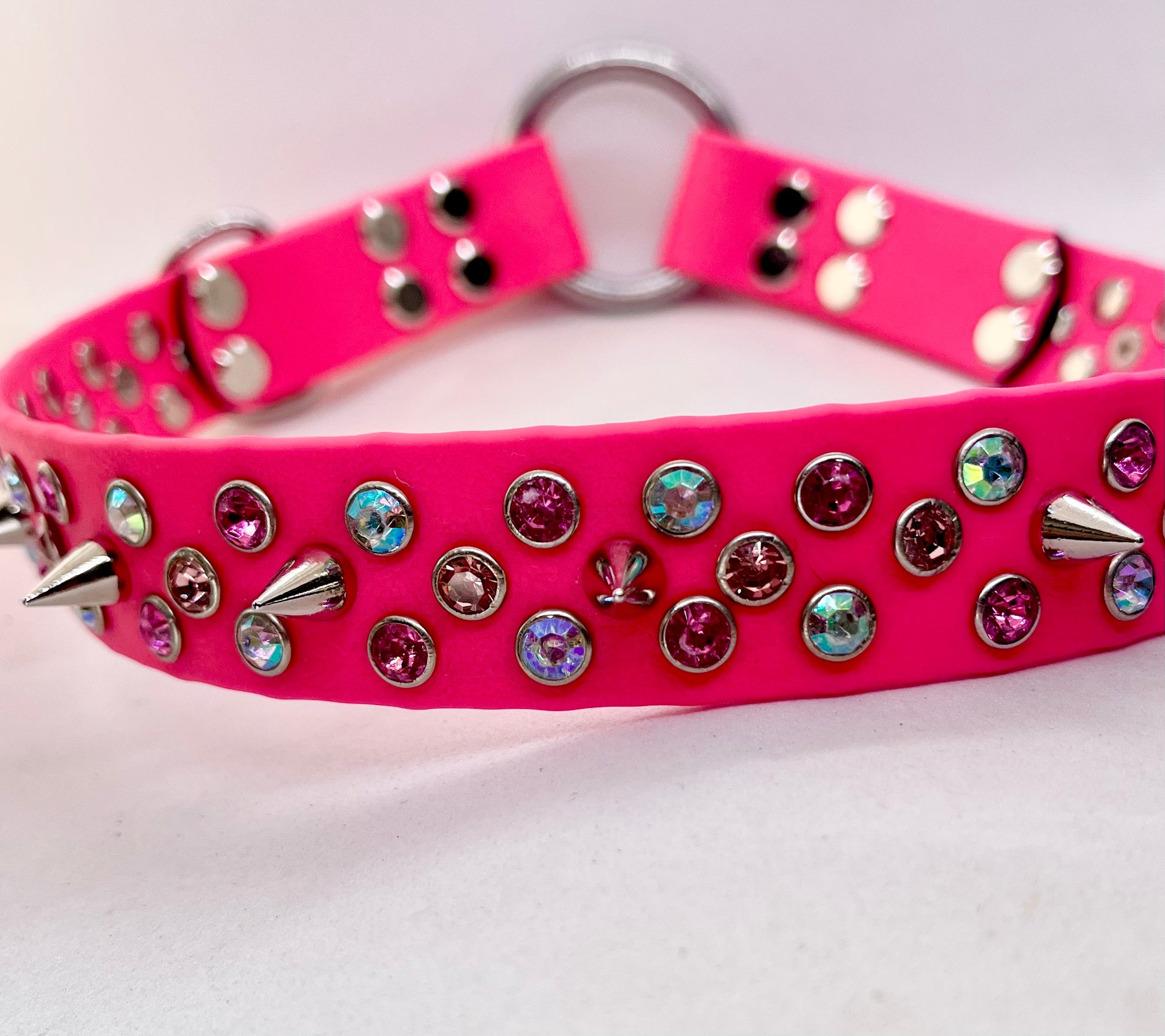 Neon pink BioThane dog collar crossed flat lay showing rhinestone crystals, spikes and stainless steel O ring