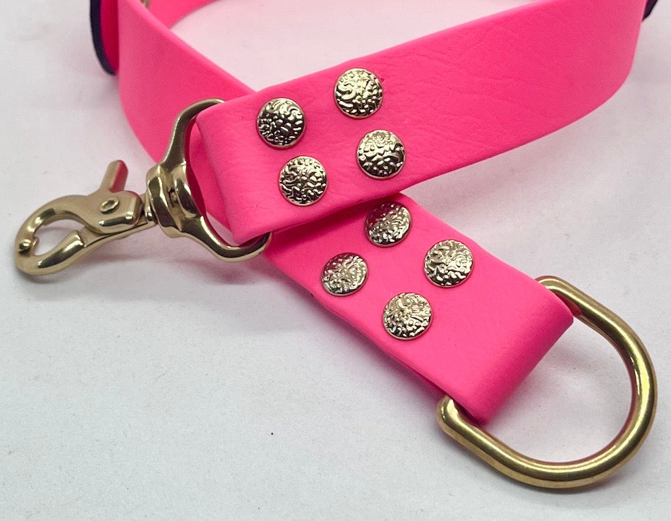 A bright neon pink collar with solid brass hardware, featuring textured round studs and a solid brass D-ring. JOOLS LONDON
